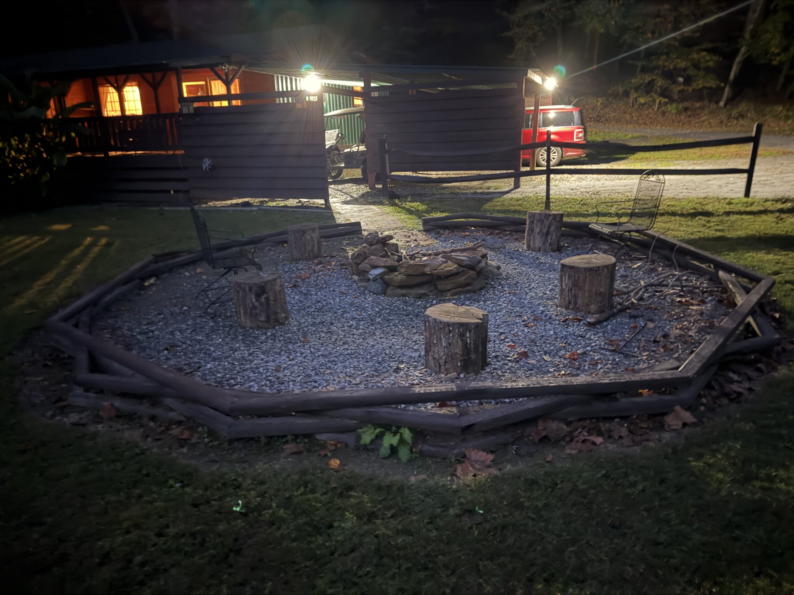 Night photo of the firepit, with the cabin security lights on behind it